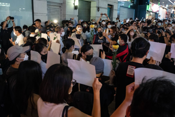 People in Hong Kong hold sheets of blank A4 paper and flowers to protest against COVID-19 restrictions in mainland China.