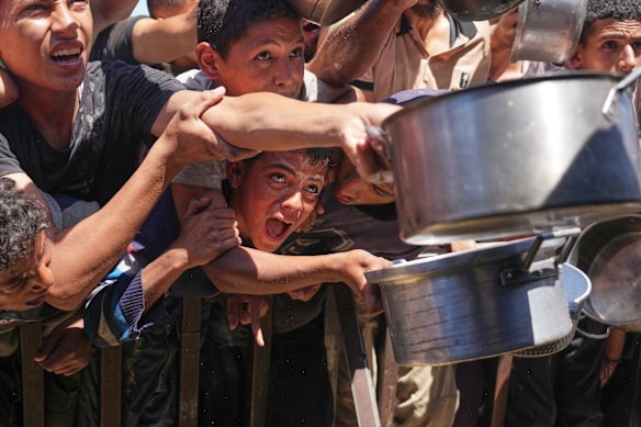 Palestinians struggle to receive cooked food distributed at a community kitchen in Khan Younis.