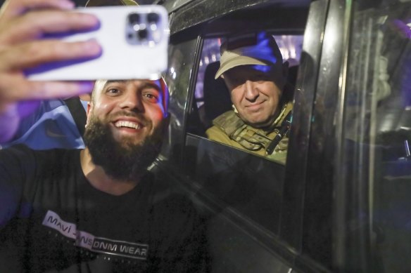 Yevgeny Prigozhin, the owner of the Wagner Group military company, right, sits inside a military vehicle posing for a selfie photo with a local civilian on a street in Rostov-on-Don on Saturday.