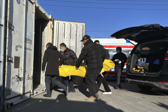 Workers transfer a body into a container for storage at a crematorium in Beijing last weekend.
