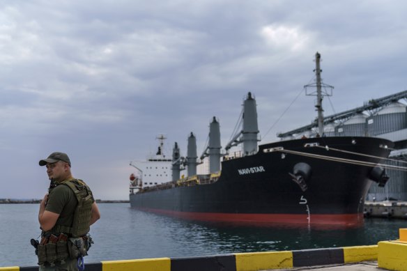 A security officer stands next to a ship full of grain since Russia’s invasion of Ukraine began five months ago as it waits to sail from the Odesa Sea Port, in Odesa.