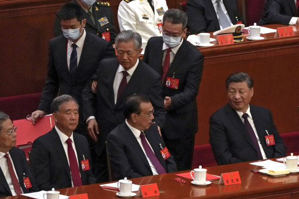 Chinese President Xi Jinping (right) watches as former president Hu Jintao touches Premier Li Keqiang as he is escorted to leave.