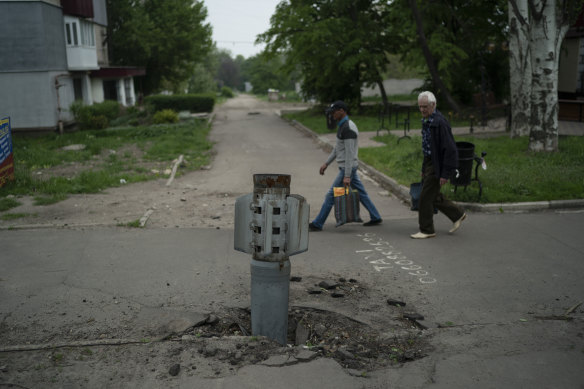 People walk past part of a rocket that sits wedged in the ground in Lysychansk, Luhansk region, in May. The region is not almost entirely under Russian control.