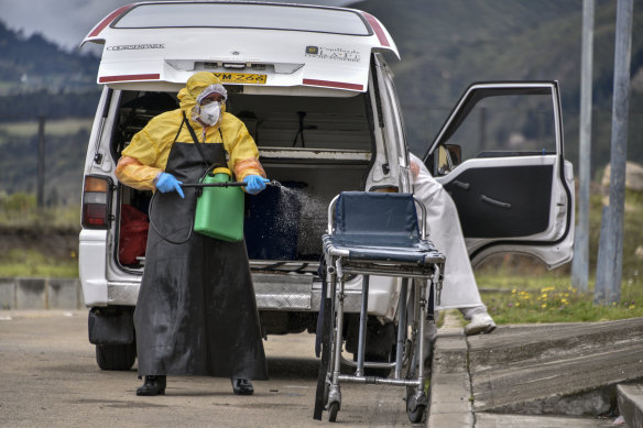 A funeral worker sanitises equipment used to transport the body of a person who died from COVID-19 in Bogota.
