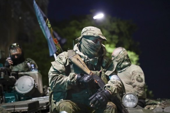 Members of the Wagner Group military company sit atop a tank on a street in Rostov-on-Don.