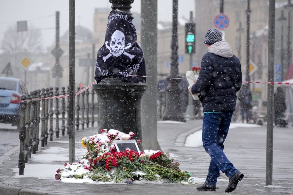 A man arrives to lay flowers near the site of an explosion at the “Street Bar” cafe in St Petersburg, Russia.