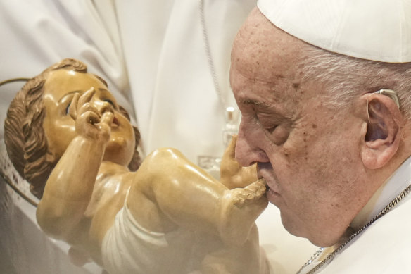 Pope Francis kisses a wooden statuette of the infant Jesus at the end of a mass in St Peter’s Basilica at the Vatican on New Year’s Day in 2025.