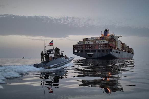 In this photo released by Iran’s semi-official Tasnim News Agency, an Iranian Revolutionary Guard speedboat approaches a cargo ship in the Strait of Hormuz on April 21.