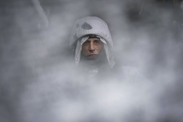 A Ukrainian serviceman, seen through a camouflage mesh, stands at a frontline position in the Luhansk region, eastern Ukraine.