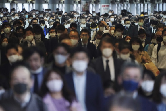 A station passageway is crowded with commuters wearing face masks to help curb the spread of the coronavirus during a rush hour in Tokyo. 