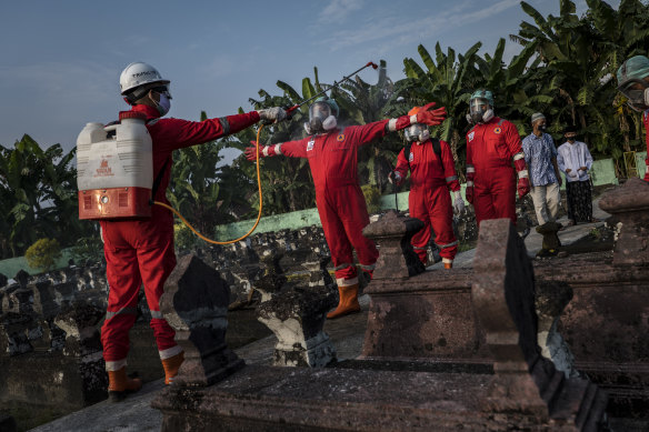 A volunteer in Yogyakarta is sprayed with disinfectant after conducting a burial the body of a woman suspected to have died from COVID-19. 