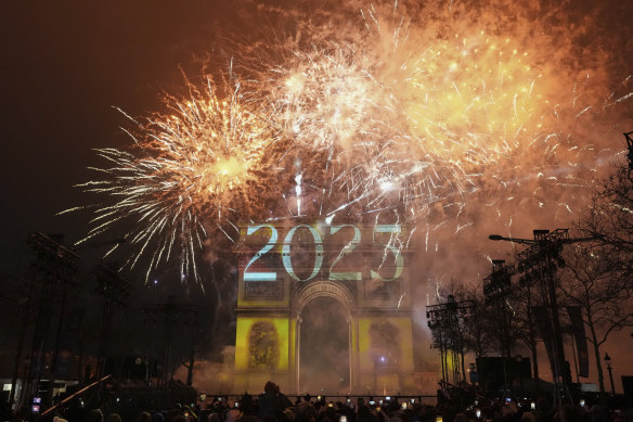 A light show is projected on the Arc de Triomphe as fireworks explode during New Year’s celebrations on the Champs Elysees in Paris, France.