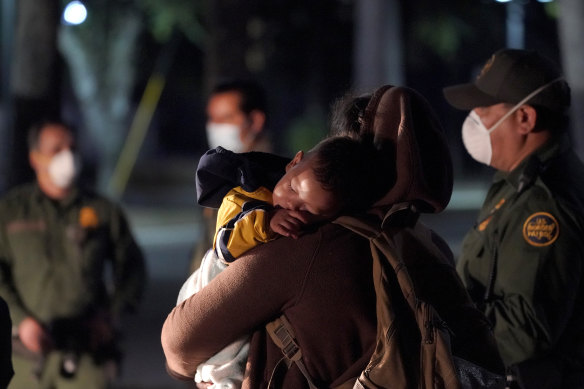 A migrant child sleeps on the shoulder of a woman at an intake area after turning themselves in upon crossing the US-Mexico border in the early hours of Wednesday.