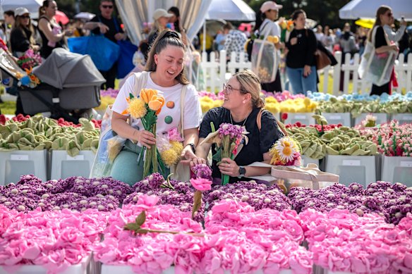 Friends Sarah Martinuz and Brianna Beckett select flowers at the Flower market by artist Cj Hendry at the Domain on Friday. The Flower Market is an immersive art installation featuring 100,000 hand-crafted plush flowers.