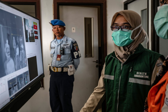 An Indonesian health official monitors international passengers as they pass a thermal scanner monitor in Yogyakarta.