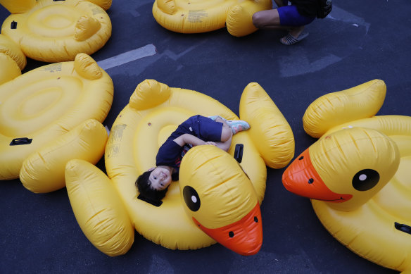 Bir çocuk, 2020'de Bangkok'ta düzenlenen bir miting sırasında protesto hareketinin sembolü olan şişme sarı ördeğin üzerinde yatıyor.
