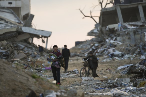 Palestinians walk along a street in Gaza City, littered with rubble from buildings destroyed during the Israeli army’s ground and air offensive.