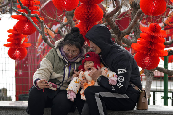 A couple take a selfie with their toddler in front of Lunar New Year decorations at a public park in Beijing on Thursday. 