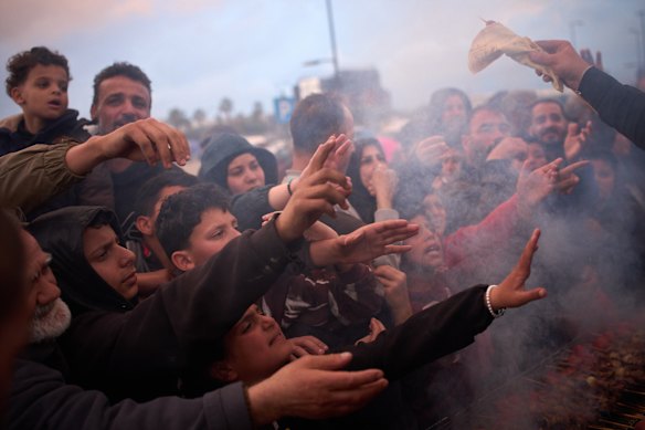 Families displaced by Israeli bombing in southern Lebanon reach for food donations in Beirut.