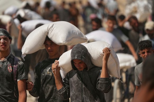 Palestinians carry sacks of flour taken from a humanitarian aid convoy en route to Gaza City on Friday.