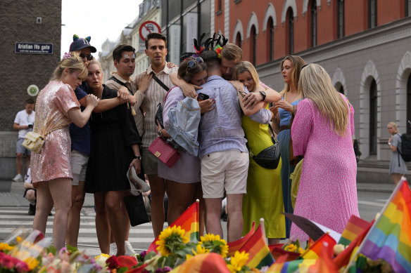 People comfort each other as they stand at the scene of a shooting in central Oslo on Saturday, June 25.