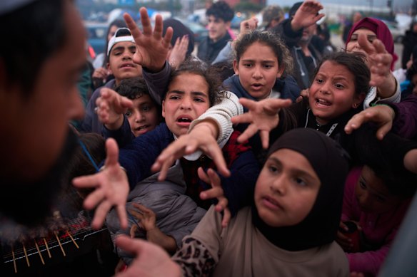 Displaced children clamour for donated food after fleeing Israeli bombardment in southern Lebanon.