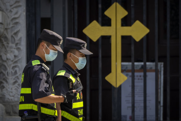 Security officers on patrol walk past the gates of the Wangfujing Church, a Catholic church in Beijing.