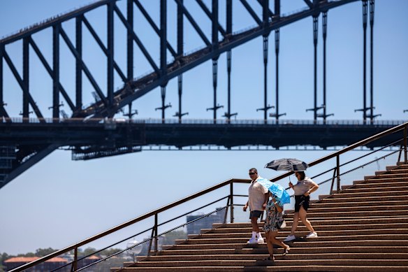 People shield themselves from the sun as they descend the Sydney Opera House steps.