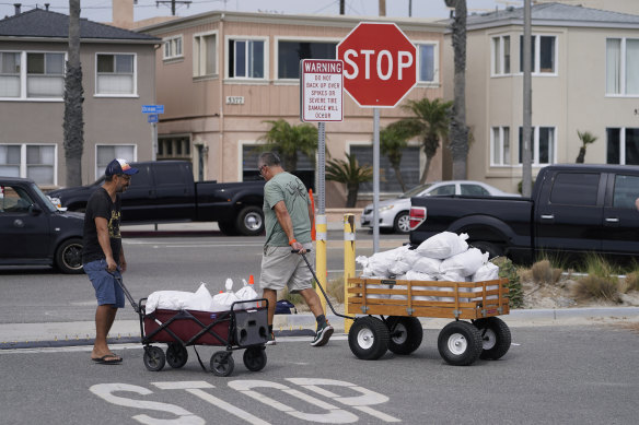 Long Beach residents pull wagons with sandbags.