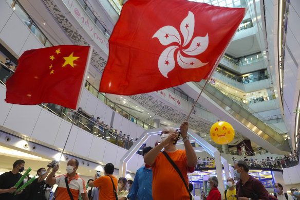 People wave a Hong Kong flag and a Chinese national flag as they watch Olympics events at a shopping mall in Hong Kong on Friday, July 30. 