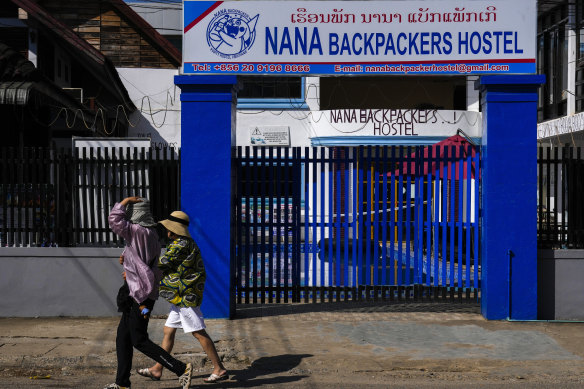 Foreign tourists walk past the closed Nana Backpackers hostel in Vang Vieng.