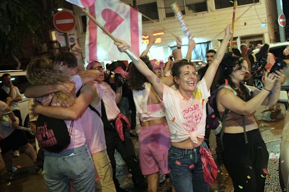 People embrace and wave flags amid falling confetti as they celebrate early exit poll results for Israel’s general election in Tel Aviv.