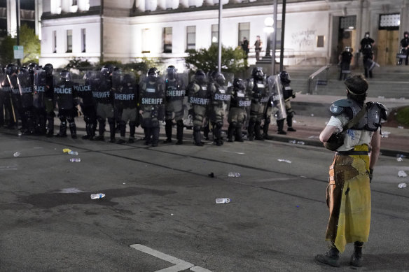 A protester faces off with police in riot gear outside the Kenosha County Courthouse late on Monday.