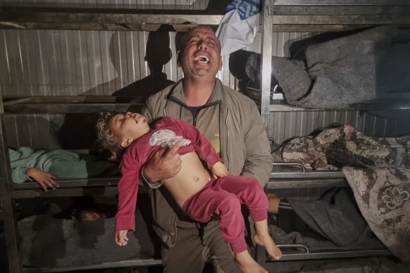 A man holds the body of an unidentified child, as he searches for his nephew at the morgue of the hospital in Khan Younis after Israeli airstrikes. 