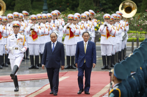 Japanese Prime Minister Yoshihide Suga, right, and his Vietnamese counterpart Nguyen Xuan Phuc, left, attend a welcoming ceremony at the Presidential Palace in Hanoi, Vietnam.