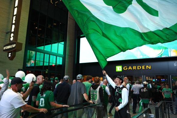 Lucky the Leprechaun of the Boston Celtics waves a flag as fans enter the arena.
