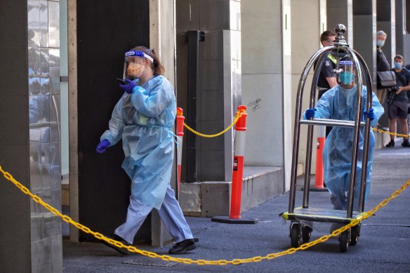 Staff in protective gear help transfer guests from the Holiday Inn on Flinders Lane on Tuesday.