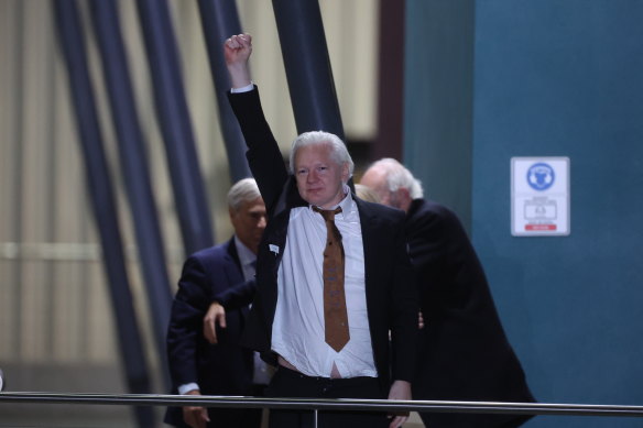 Julian Assange punches his fist in the air as he arrives in Canberra.