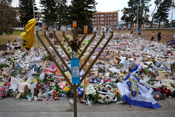 A menorah frames flowers laid in grief a week after the December 14 massacre at Bondi Beach.