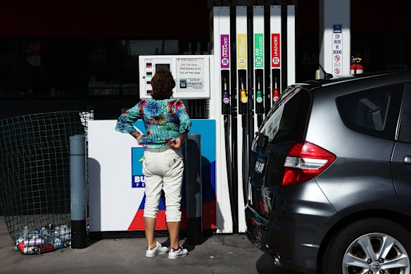 A driver reads a sign at a petrol station: “Fuel price is on the rise. Our advice is to fill up the tank.”