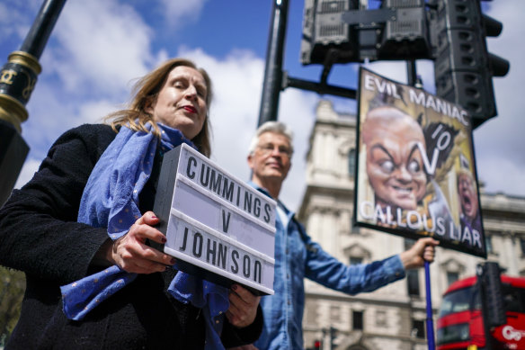 Protesters hold placards near Parliament Square, in London, on the day Dominic Cummings, the volatile advisor who until late last year was British Prime Minister Boris Johnson’s most powerful and trusted aide, appeared at a commitee hearing.