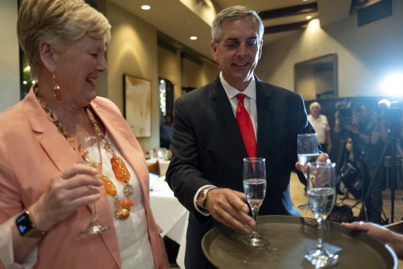 Georgia Secretary of State Brad Raffensperger, grabs a glass of champagne to toast with his wife Tricia after declaring victory. 