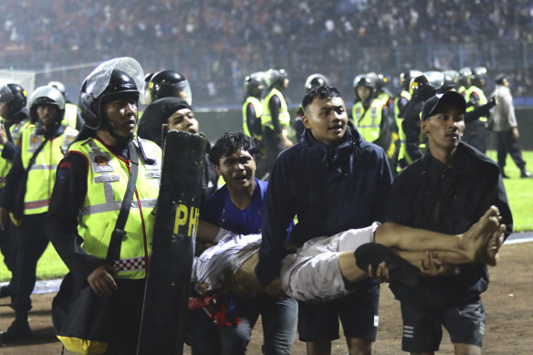 Soccer fans carry an injured man following clashes during a soccer match at Kanjuruhan Stadium in Malang, East Java, Indonesia, Saturday, October 1, 2022.