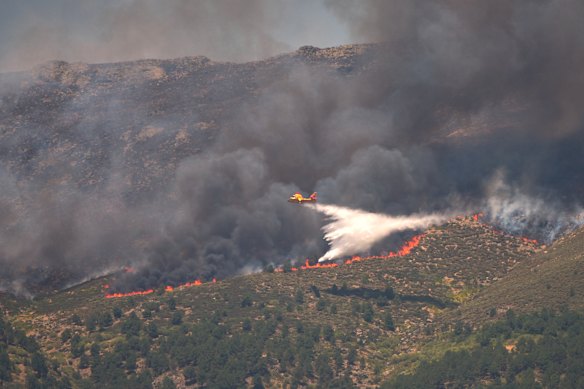 A seaplane drops water onto the fire as a wildfire advances near La Adrada in Spain.
