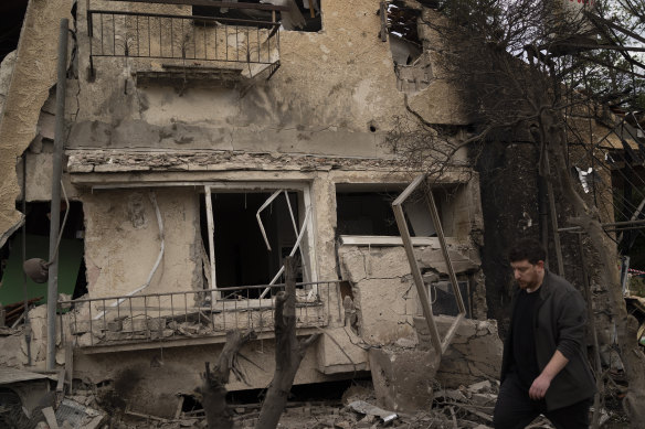 A man walks past a damaged building after a rocket fired from Lebanon hit an area in Rinatya on the outskirts of Tel Aviv.