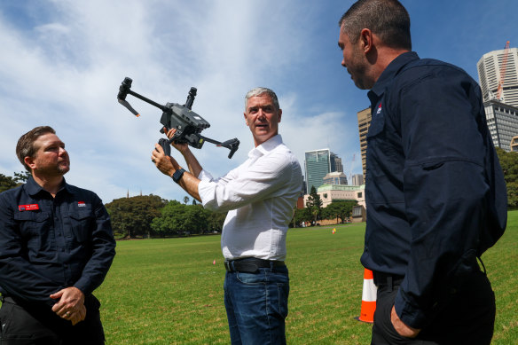 Minister for Roads John Graham and drone operators examine one of the drones that is helping manage the road network.