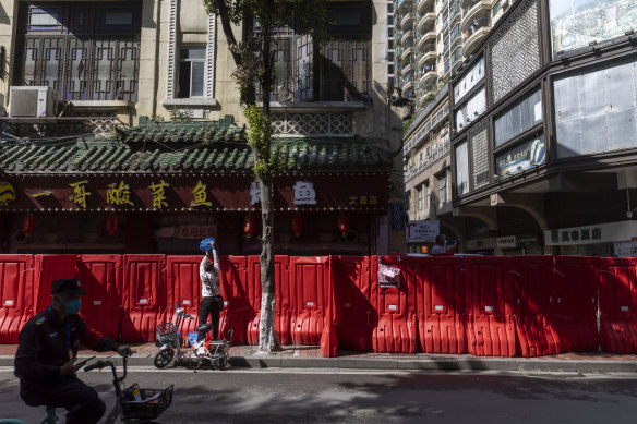 Bir mukim, Guangzhou'daki bir konut bloğunu kapatmak için kurulan geçici bir bariyerden eşyalarını geçirir. 