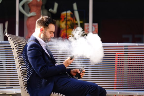 A man vapes on Bourke Street. 