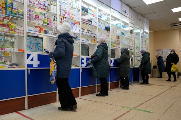 Customers stand at the windows buying medicines in a pharmacy in St Petersburg, Russia, last week.