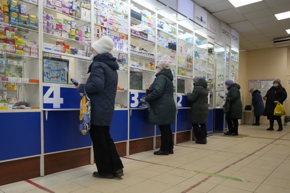 Customers stand at the windows buying medicines in a pharmacy in St Petersburg, Russia, last week.